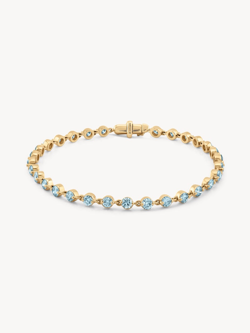 Gold bracelet with aquamarine gemstones on a white background